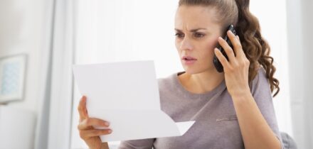 concerned-young-woman-holding-letter-and-talking-mobile-phone